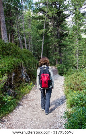 woman walking on a path in the woods with a backpack