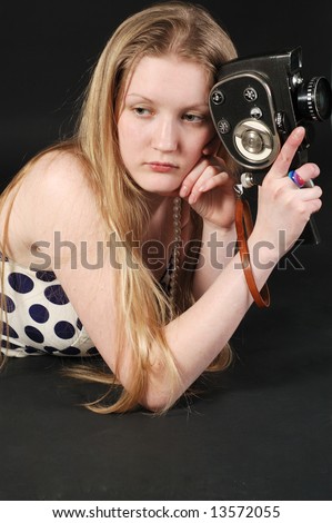 Sad long haired girl holding a vintage movie camera