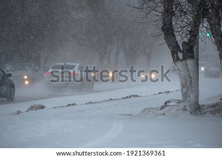 Snow-covered road with cars in a storm,blizzard or snowfall in winter in bad weather in the city.Extreme winter weather conditions in the north.Cars drive through the snow-covered streets of the city Foto stock © 