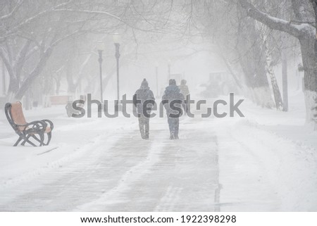 A snow-covered road with people in a storm,blizzard or snowfall in winter in bad weather in the city.Extreme winter weather conditions in the north.People walk through the streets under heavy snowfall Foto stock © 