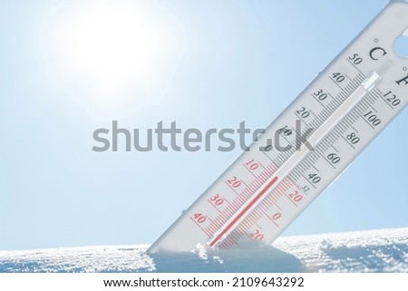 In winter or spring the thermometer lies on the snow and shows a negative temperature in cold weather.Meteorological conditions with low air and ambient temperatures.Climate change and global warming Foto stock © 