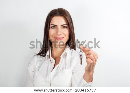 Young happy smiling business woman or real estate agent showing keys from new house, isolated over white background