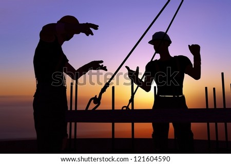 Silhouettes of workers against the evening sky.