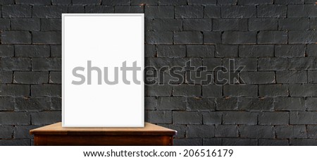 blank frame on wood table at long black brick wall,leave space for your content