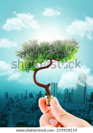 hand holding tree refreshing on light bulb on sky with cloud and cityscape,eco concept,Clear pollution at city with green ideas.
