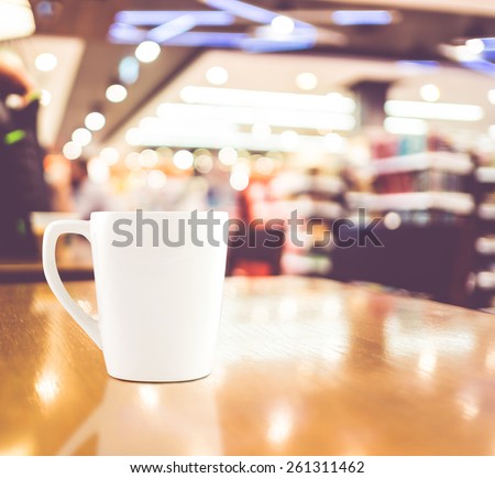 Vintage filter : White coffee cup on wood table at blur cafe background with bokeh light
