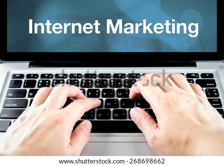 hand type on laptop with internet marketing on screen with blur blue background, business concept.