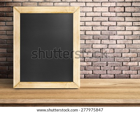 Blank blackboard on wooden table at red brick wall,Template mock up for adding your design and leave space beside frame for adding more text.