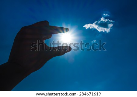 Silhouette of Hand picking sun at blue sky and cloud