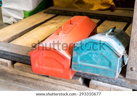 grunge red and blue metal tool boxes on wood palette in factory.