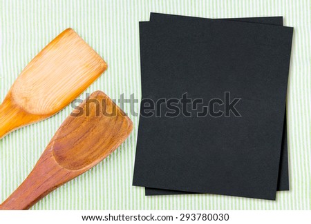 Wood spoon on green table cloth with blank black menu paper, Mock up for adding your design
