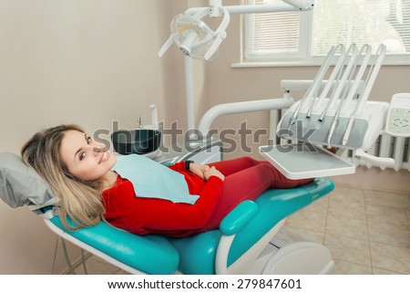 Side view of smiling female patient with dentist in the dentists chair