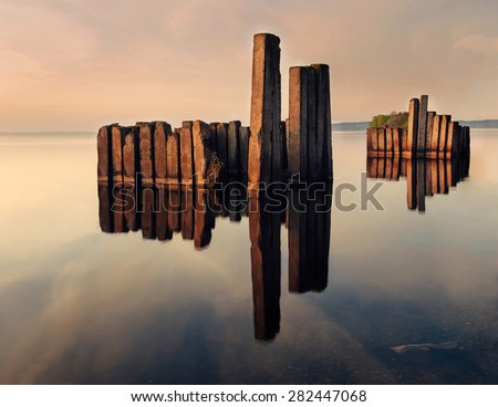 Bridge columns in water on long exposure with sunset on background