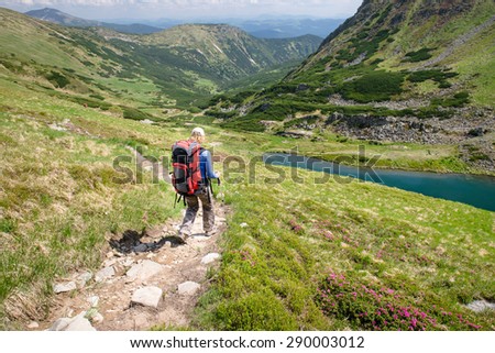 Young woman hiking with sticks and backpack in the beautiful mountains landscape