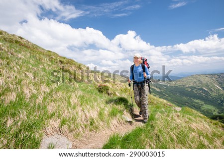 Young woman hiking with sticks and backpack in the beautiful mountains landscape