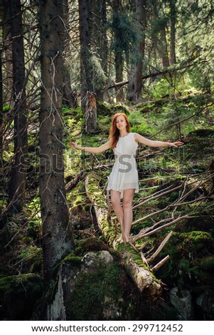 Fairytale woman walking on the fallen tree in the mystery mountain forest