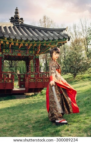 Korean woman or geisha in kimono holding samurai sword near face