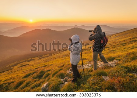 Nature photographers with digital camera and tripod on top of the mountain at sunset