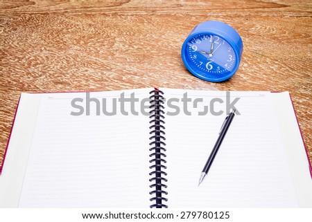blue alarm clock and notebook on table, business concept