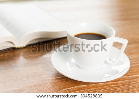 cup of coffee and book on wooden table
