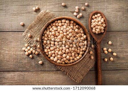 Wooden bowl and wooden spoon full of chickpeas on wooden background. Top view. Stockfoto © 