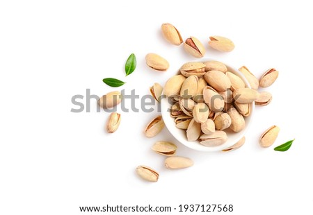 Pistachio nuts in small bowl isolated on white background. Top view. Copy space.