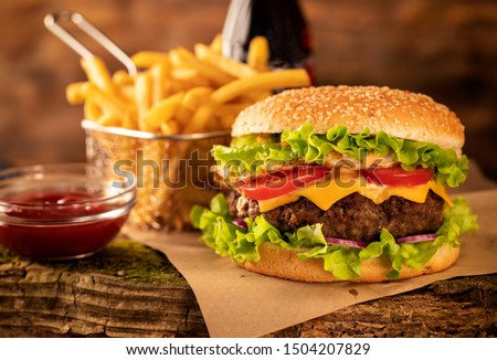 
Hamburger with cheese and fried potatoes on a wooden table