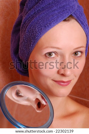 Beautiful young woman with the mirror in the bathroom.