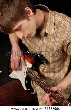 young musician playing electric guitar isolated on black