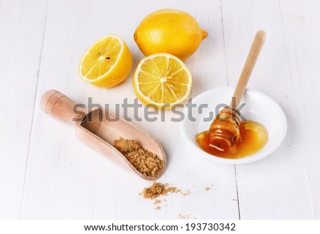 Group of organic lemons with honey and brown sugar over white wooden background