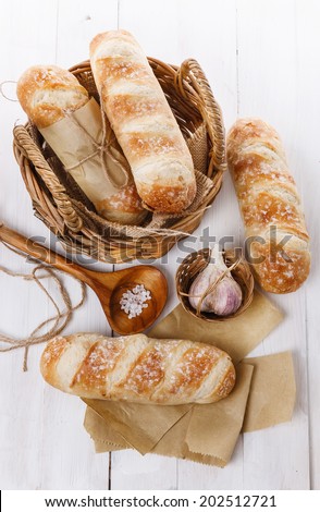 Stone Baked Pane Di Casa bread rolls, garlic and salt on a white wooden background