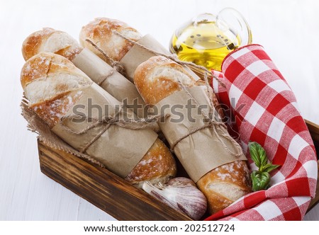 Stone Baked Pane Di Casa bread rolls in a wooden box on a white wooden background