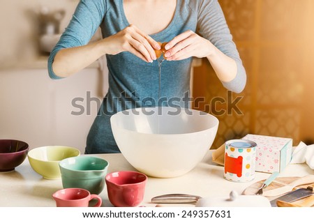 Baking concept. Female hands pouring bitten egg into a plastic bowl