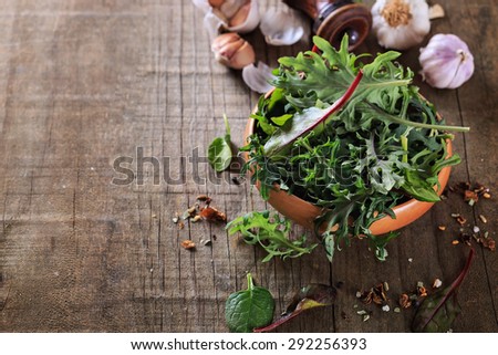 Leafy green mix of kale, spinach, baby beetroot leaves over rustic wooden background