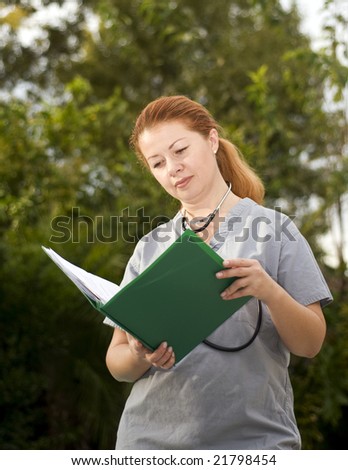 Beautiful lady doctor standing outside of a hospital and reading documents