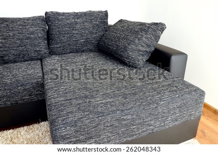 Modern black and white cloth sofa with black leather and pillows on shaggy carpet