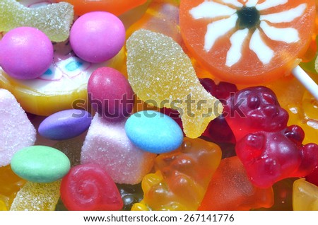 Macro detail of lollipop, gummy bears and sour candy on colored smarties background