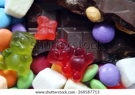 Macro detail of gummy bears, chocolate and sour candy on colored smarties background