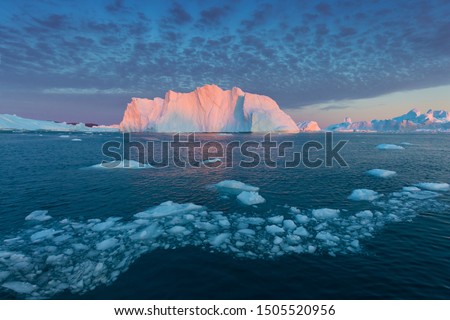 Iceberg at sunset. Nature and landscapes of Greenland. Disko bay. West Greenland.
Summer Midnight Sun and icebergs.
Big blue ice in icefjord. Affected by climate change and global warming.