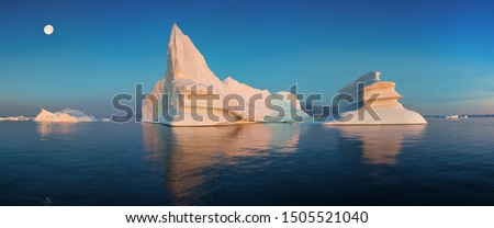 Iceberg at sunset. Nature and landscapes of Greenland. Disko bay. West Greenland.
Summer Midnight Sun and icebergs.
Big blue ice in icefjord. Affected by climate change and global warming.