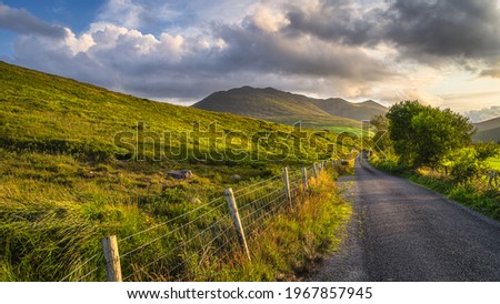 Winding country road leading toward highest mountain in Ireland, Carrauntoohil in MacGillycuddys Reeks mountains at sunset, Ring of Kerry, Ireland Stok fotoğraf © 