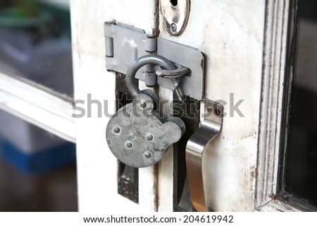 Close up photo of lock in unlock action on white wooden vintage door photo caption with daytime natural light.