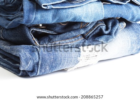 Blue denim jeans many pairs in bright color tone fold and stack up together. In the scene present the tear up surface to show the old and vintage style texture background.