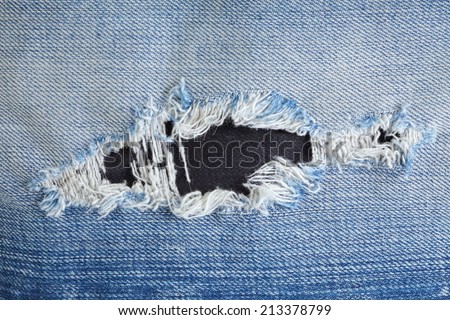 Blue denim jeans in bright color tear up surface condition present the old damaging fabric damaged detail of texture background.