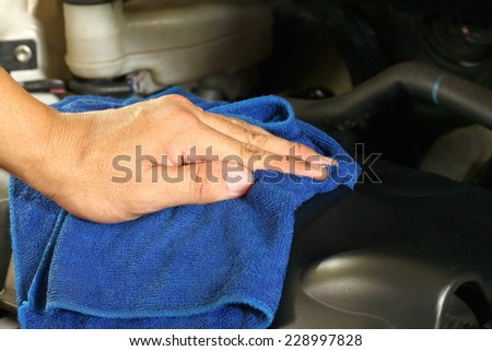 Man hand in action of do cleaning of car engine by use the blue color small micro fiber cloth in the scene focus to the man hand