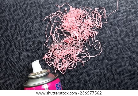 Party foam spray can focusing at spray head and nose put on black color leather background in the scene appear the pink foam string also.