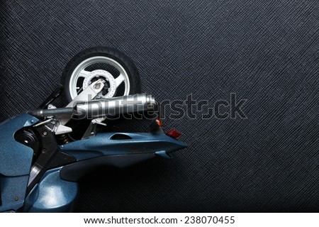 Old and dirty motorcycle plastic model in action of lie down put on black color leather background represent the accidental abstract meaning.