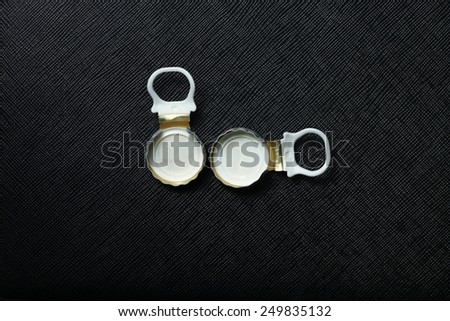 Used water bottle cap pulling type made from aluminum put on the black color leather background represent the beverage containing equipment related