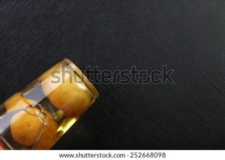 Preserved lemon pickle in the food grade plastic containing cup plate put on the black color leather surface background represent the preserved food related.