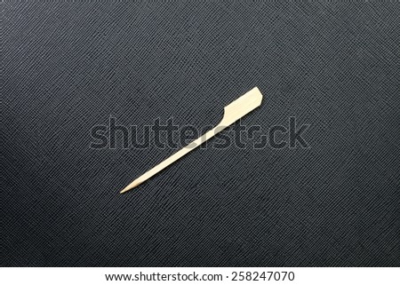 Wooden style of stick dipped fruit put on the black color leather background represent the tableware related.